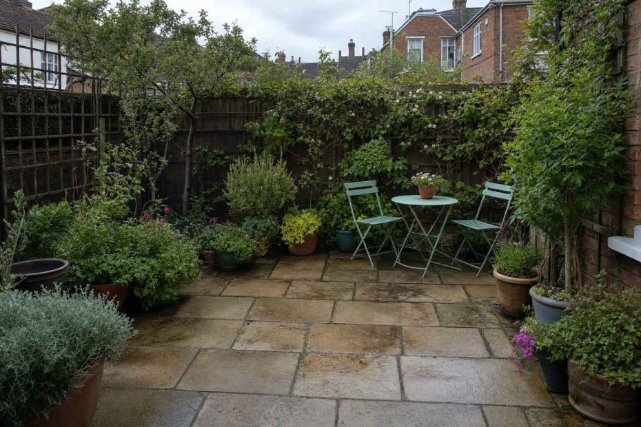 a neat, well-used small British paved garden with pots and seating