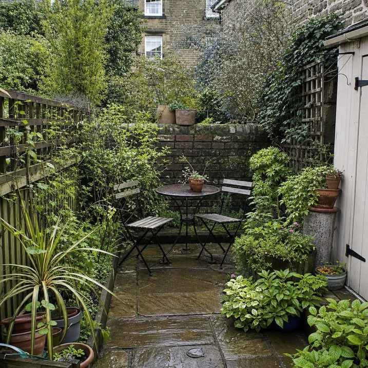 a tiny bistro seating corner surrounded by pots in a paved garden